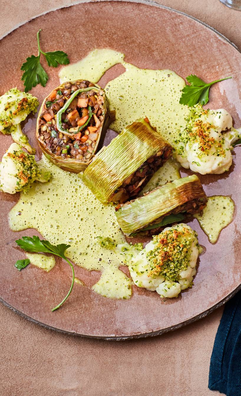 Vegane Lauch-Roulade mit Linsenfüllung in Stücken angerichtet auf einem Teller mit selbstgemachter Pistaziensoße