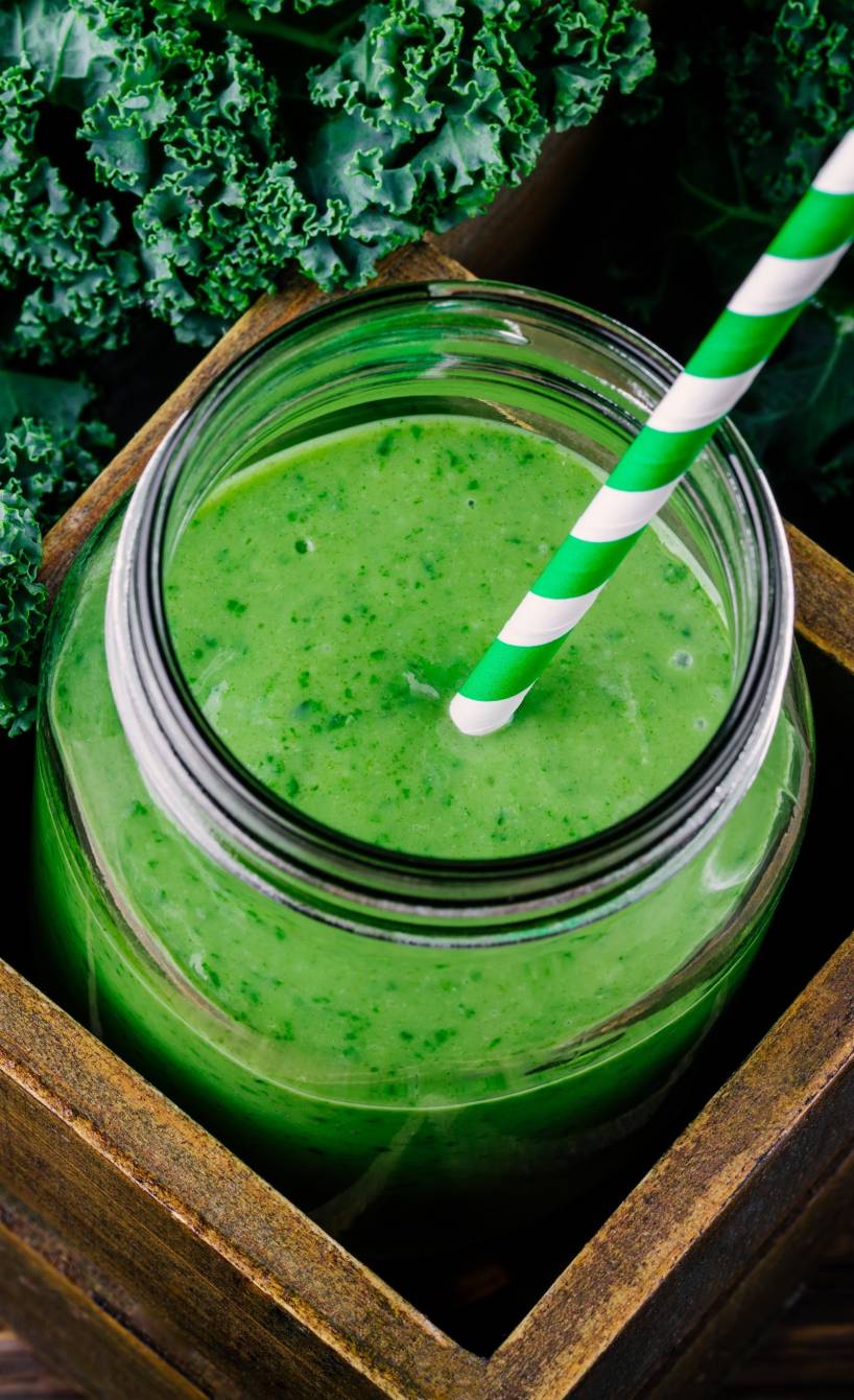 Grünkohl-Smoothie mit Apfel und Ingwer in einem Weckglas auf einem Holztisch