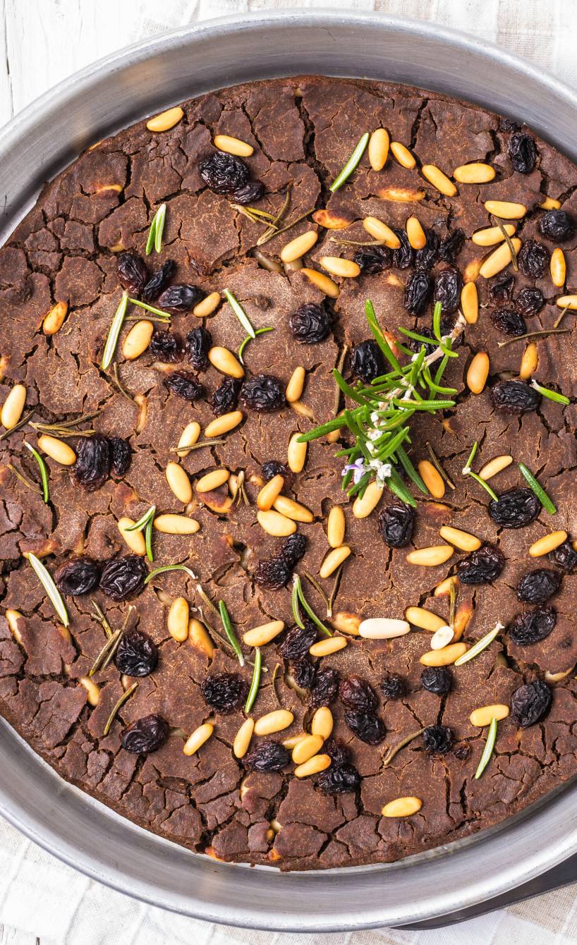 Italienischer Kastanienmehlkuchen Castagnaccio bestreut mit Rosinen und Pinienkernen in einer Springform