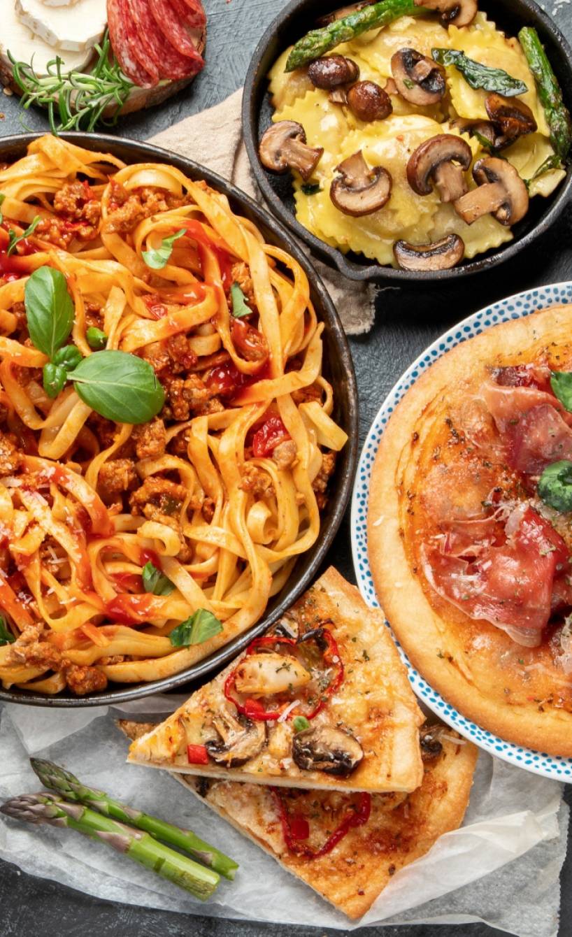 Verschiedene authentisch italienische Gerichte für Vorspeisen und Hauptgerichte stehen angerichtet auf einem dunklen Tisch Verschiedene authentisch italienische Gerichte für Vorspeisen und Hauptgerichte stehen angerichtet auf einem dunklen Tisch