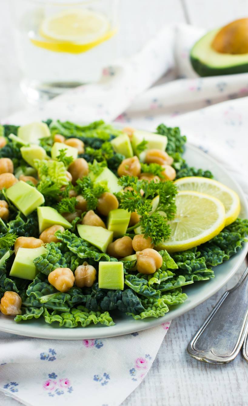 Wirsingsalat mit Avocado und Kichererbsen auf einem Teller, daneben Joghurt-Dressing