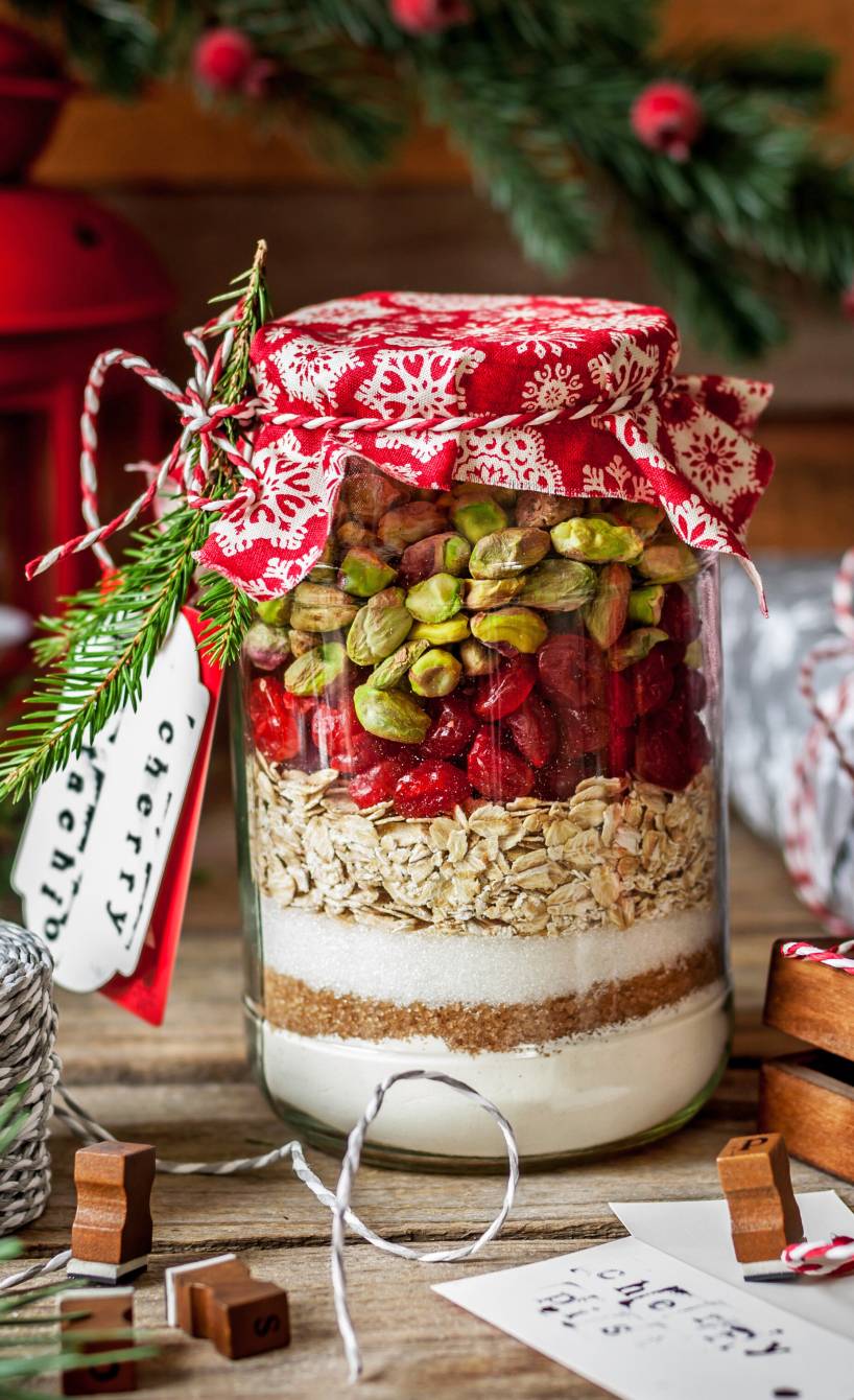 Backmischung für Hafer-Cookies mit Pistazien und Kirschen geschichtet in ein Weckglas und weihnachtlich verpackt
