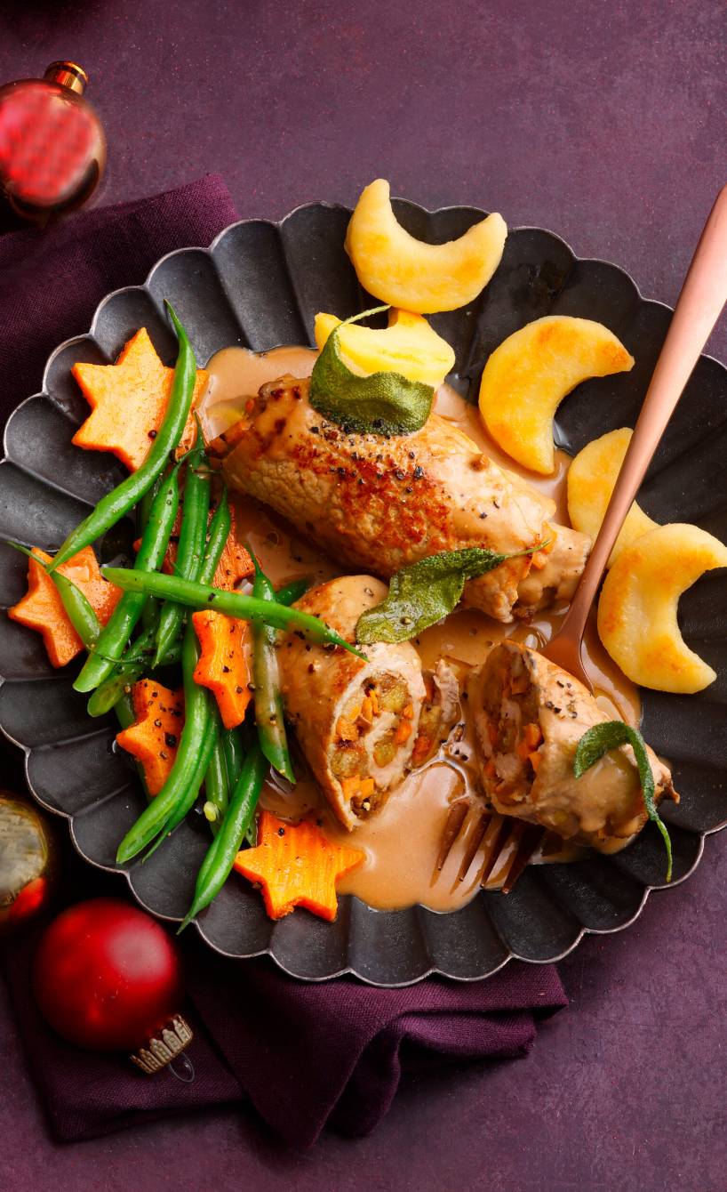 Angeschnittene, gefüllte Involtini angerichtet mit Polentamonden, Süßkartoffelsternen, grünen Bohnen und Sauce auf einem Teller