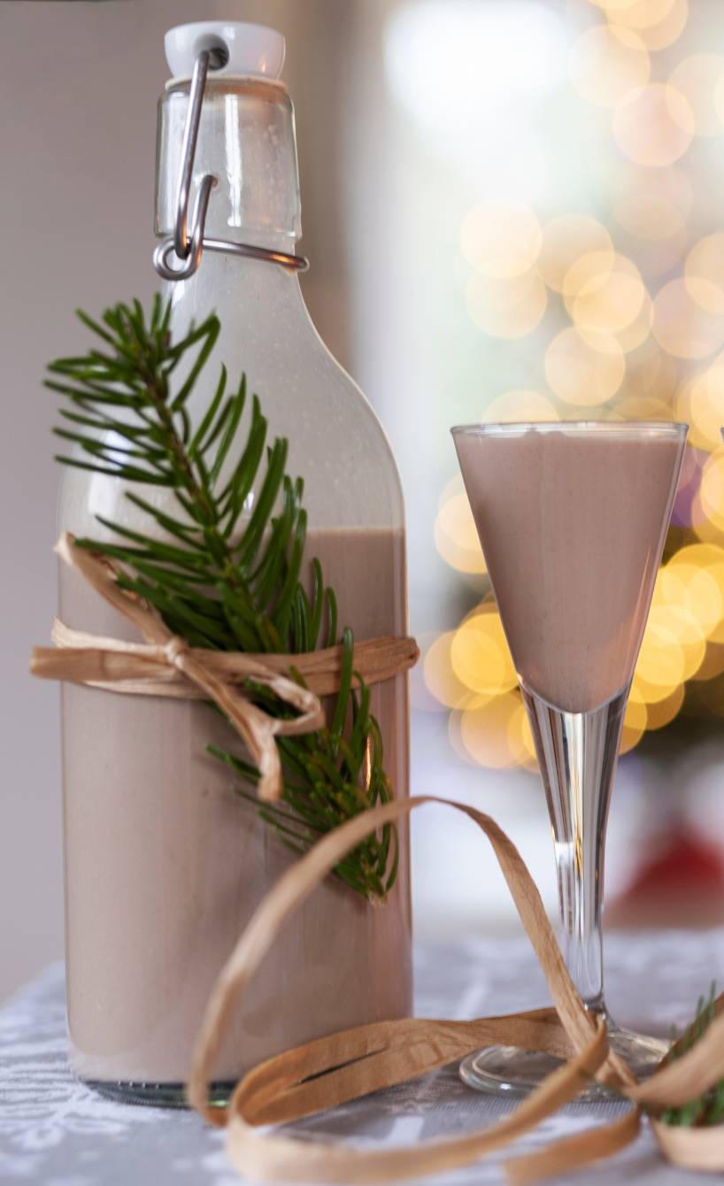 Selbst gemachter Weihnachtslikör in einer hübsch verpackten Glasflache auf einem Tisch