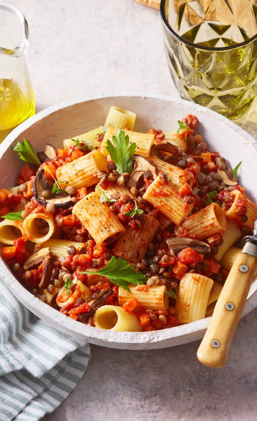 Rigatoni Nudeln mit veganer Linsenbolognese mit Champignons angerichtet auf einem Pastateller