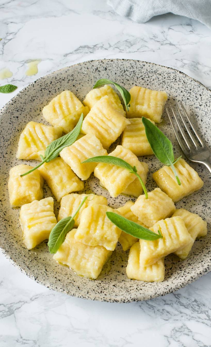 Selbstgemachte Quark-Gnocchi angerichtet mit Salbeibutter auf einem Pastateller