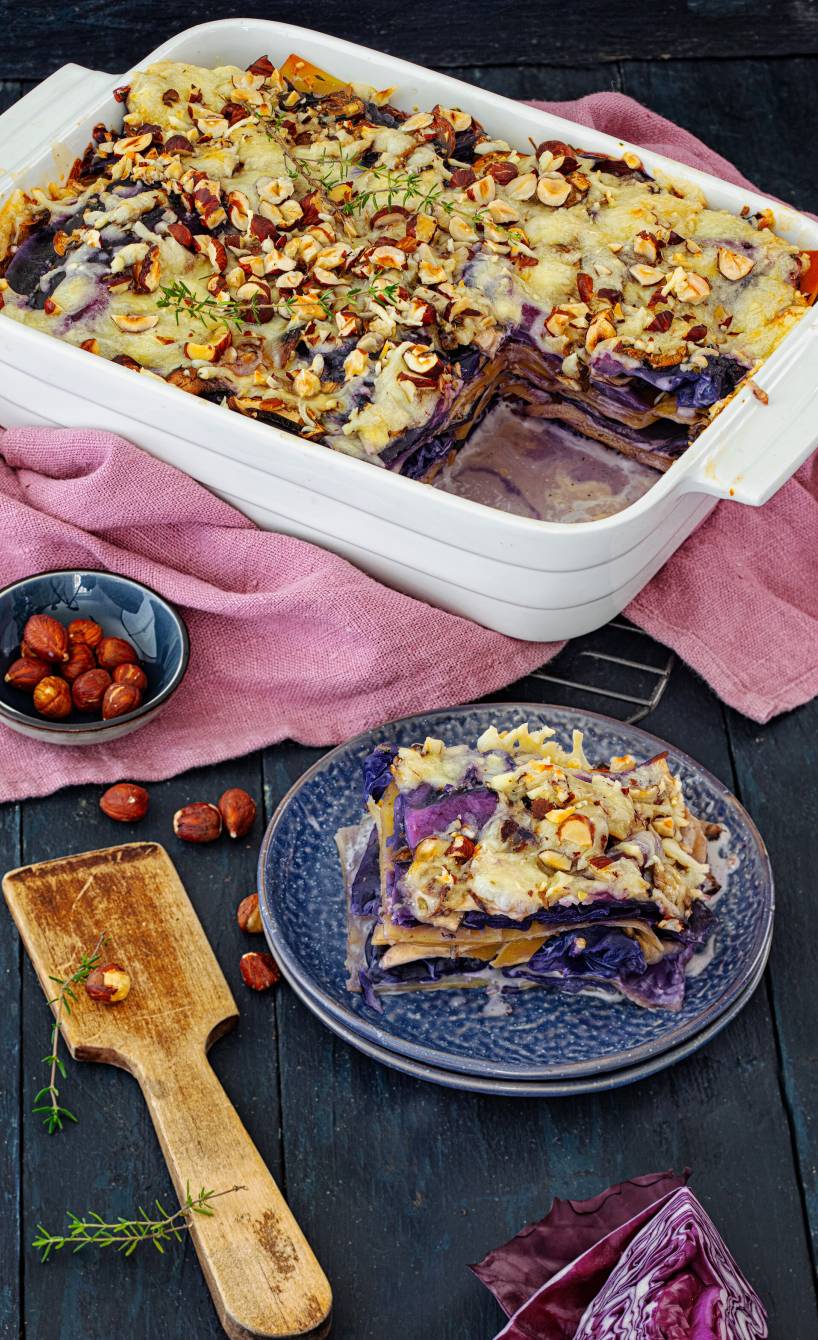 Rotkohl-Lasagne mit Champignons angeschnitten in einer Auflaufform getoppt mit käse und Haselnusskernen