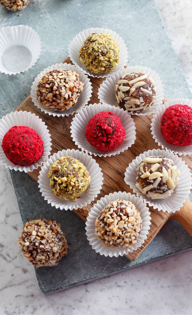 Selbstgemachte Dattelpralinen in Pralinenkapseln auf einem Holzbrett