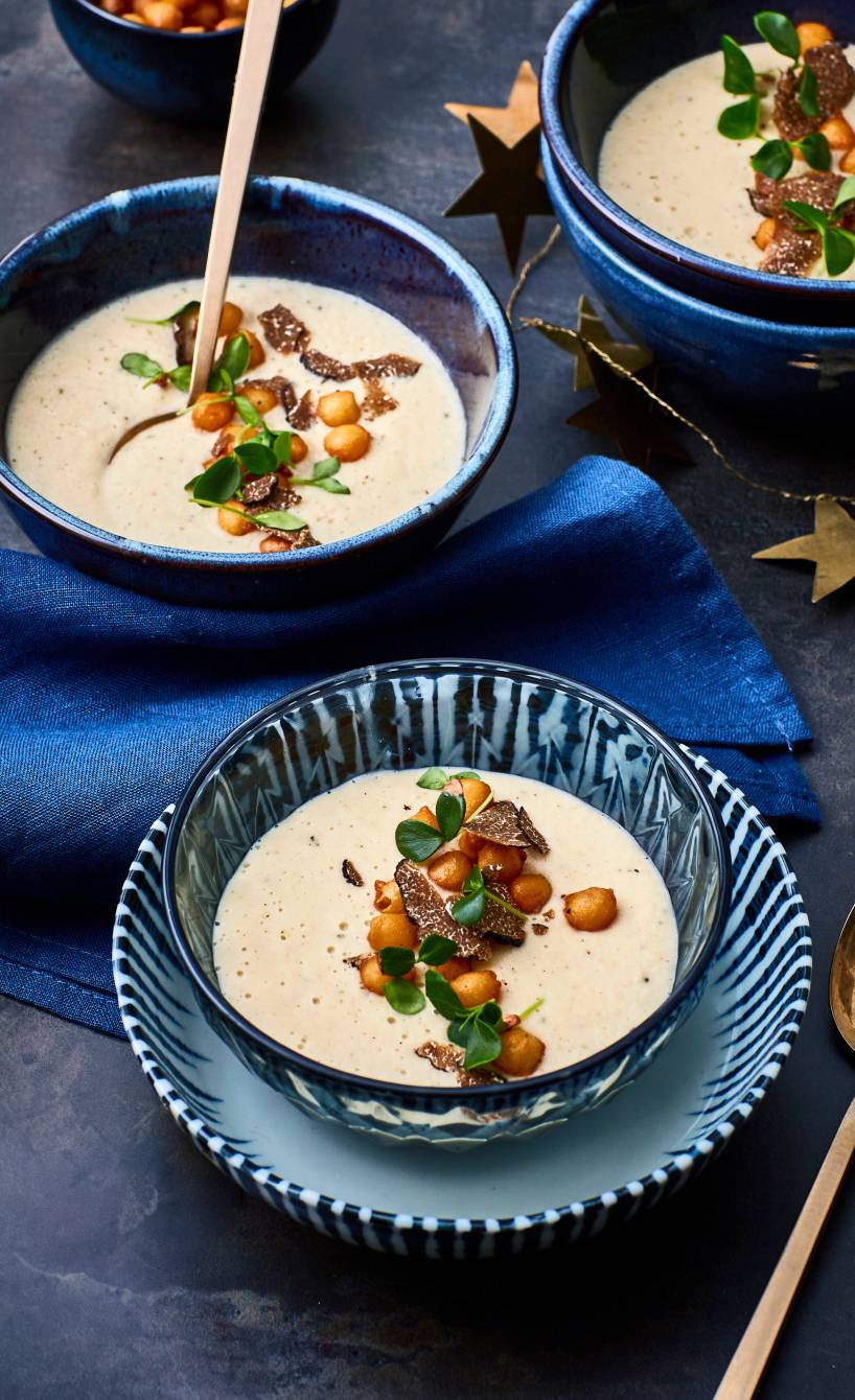 Bohnen-Creme-Suppe in mehreren Suppentellern mit Backerbesen-Einlage und Trüffelöl auf einem weihnachtlich dekorierten Tisch