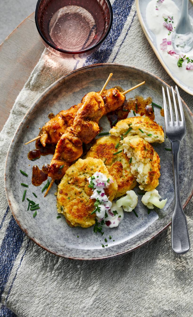 gebackene Blumenkohl-Bratlinge mit marinierten Hähnchenspießen und Quark-Dip angerichtet auf einem Teller