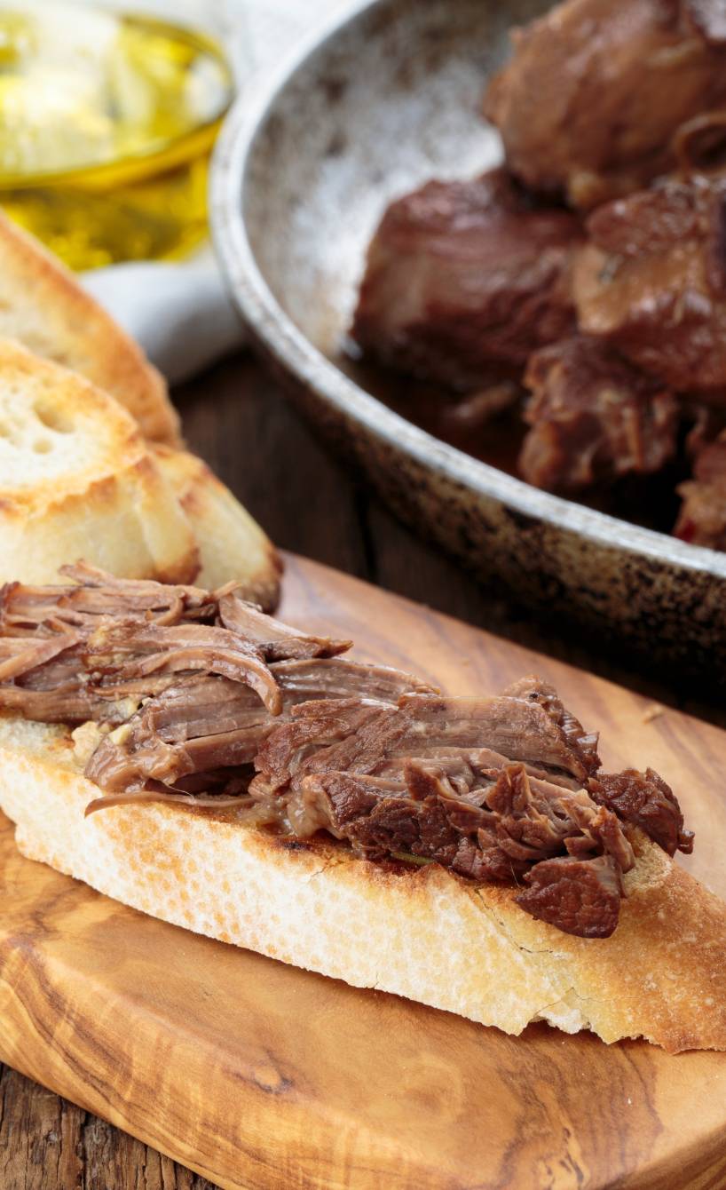 Eine Scheibe geröstetes Brot belegt mit geschmortem Rindfleisch