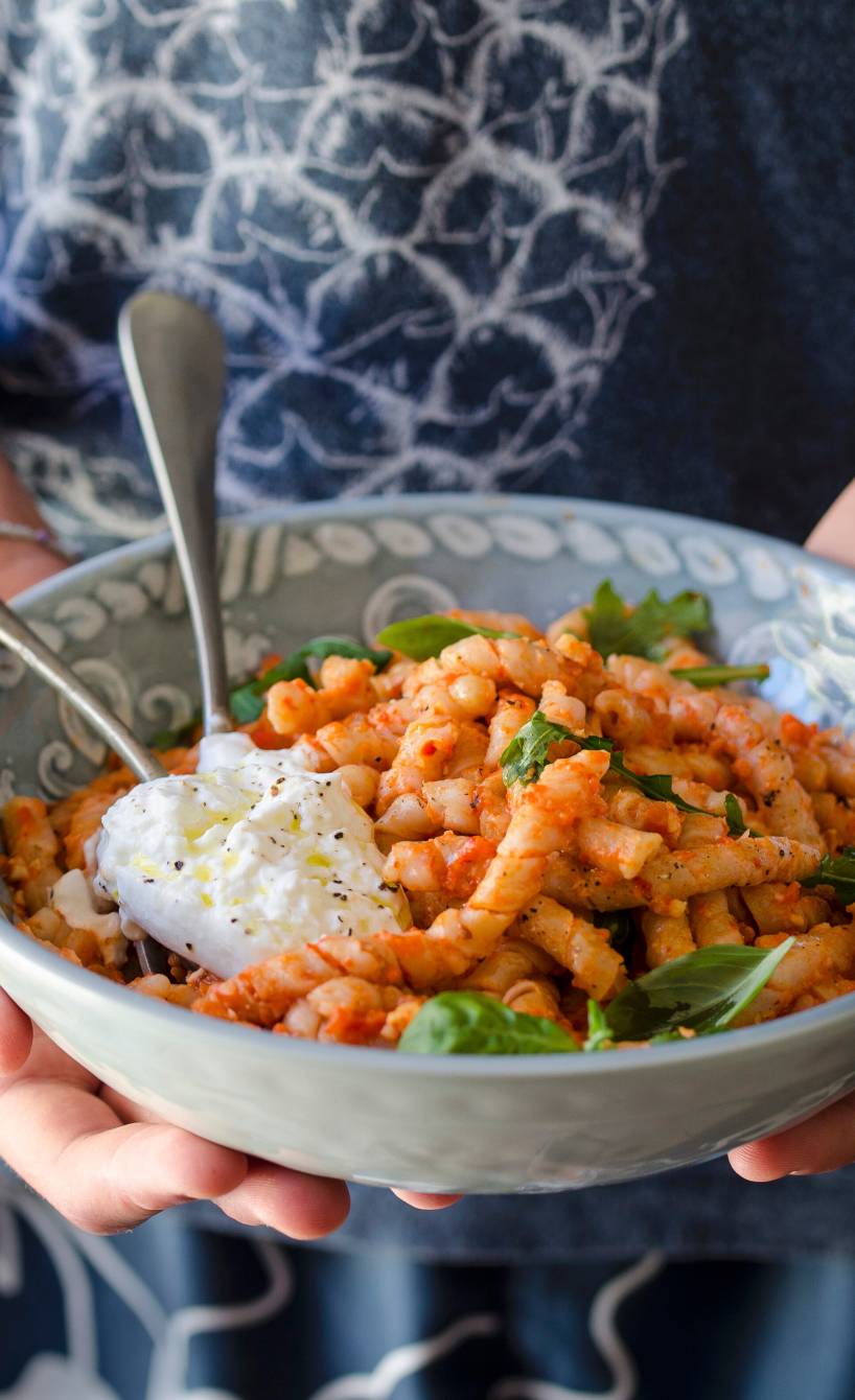 Busiate Nudeln mit geröstetem Paprika-Mandel-Pesto angerichtet mit Burrata und Rucola uaf einem Pastateller