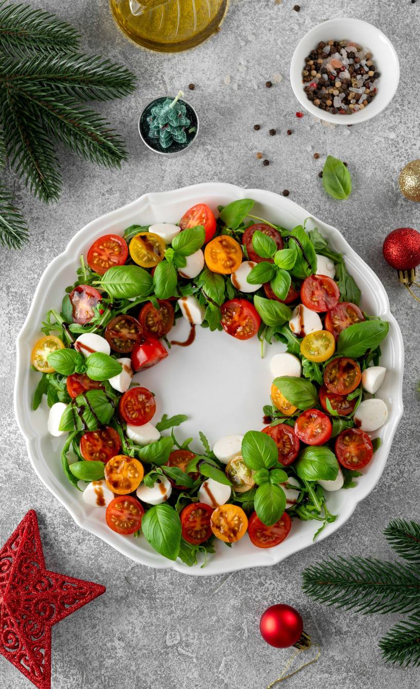Caprese  Tomate-Mozzarella-Vorspeisensalat in Form eines Weihnachtskranzes angerichtet auf einem weihnachtlich dekorierten Tisch