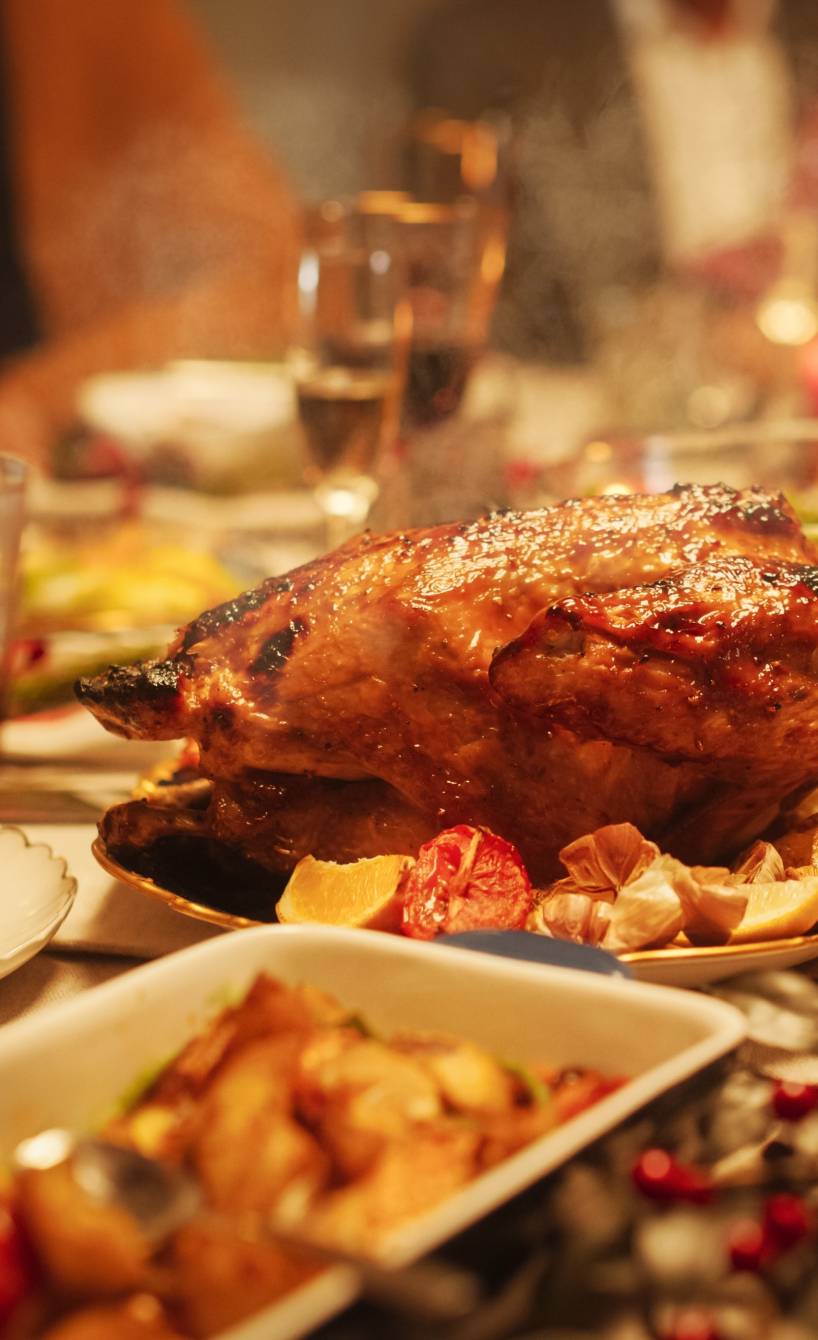 Eine gedeckte Festtafel mit Fleisch und vielen Beilagen, an dem mehrere Menschen sitzen