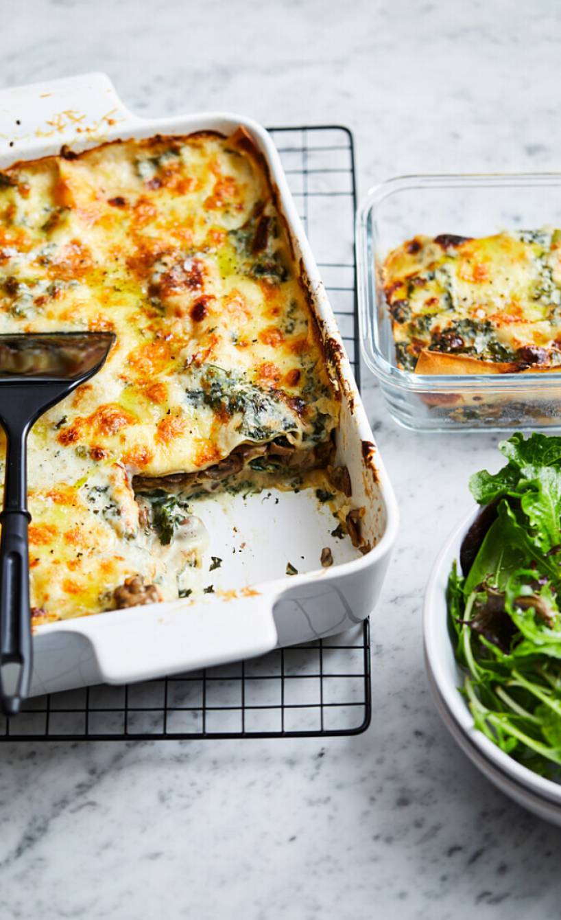 Angeschnittene Pilz-Grünkohl-Lasagne mit Käsedecke in einer Auflaufform auf einem Tisch