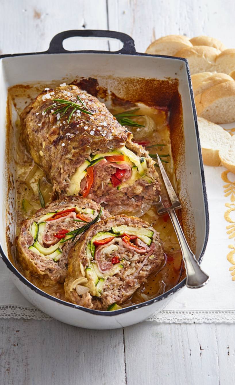 Gefüllter italienischer Hackbraten mit Zucchini und Paprika auf geschmorten Zwiebeln und Pancetta in einem Bräter