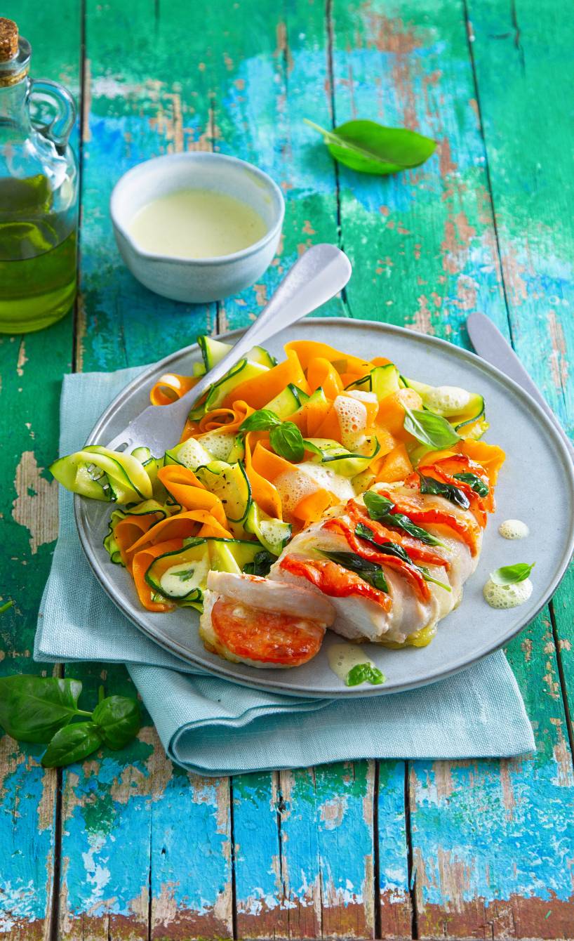 Gemüsenudeln aus Zucchini und Karotten mit Caprese-Hähnchen getoppt von Honig-Senf-Sauce auf einem Teller