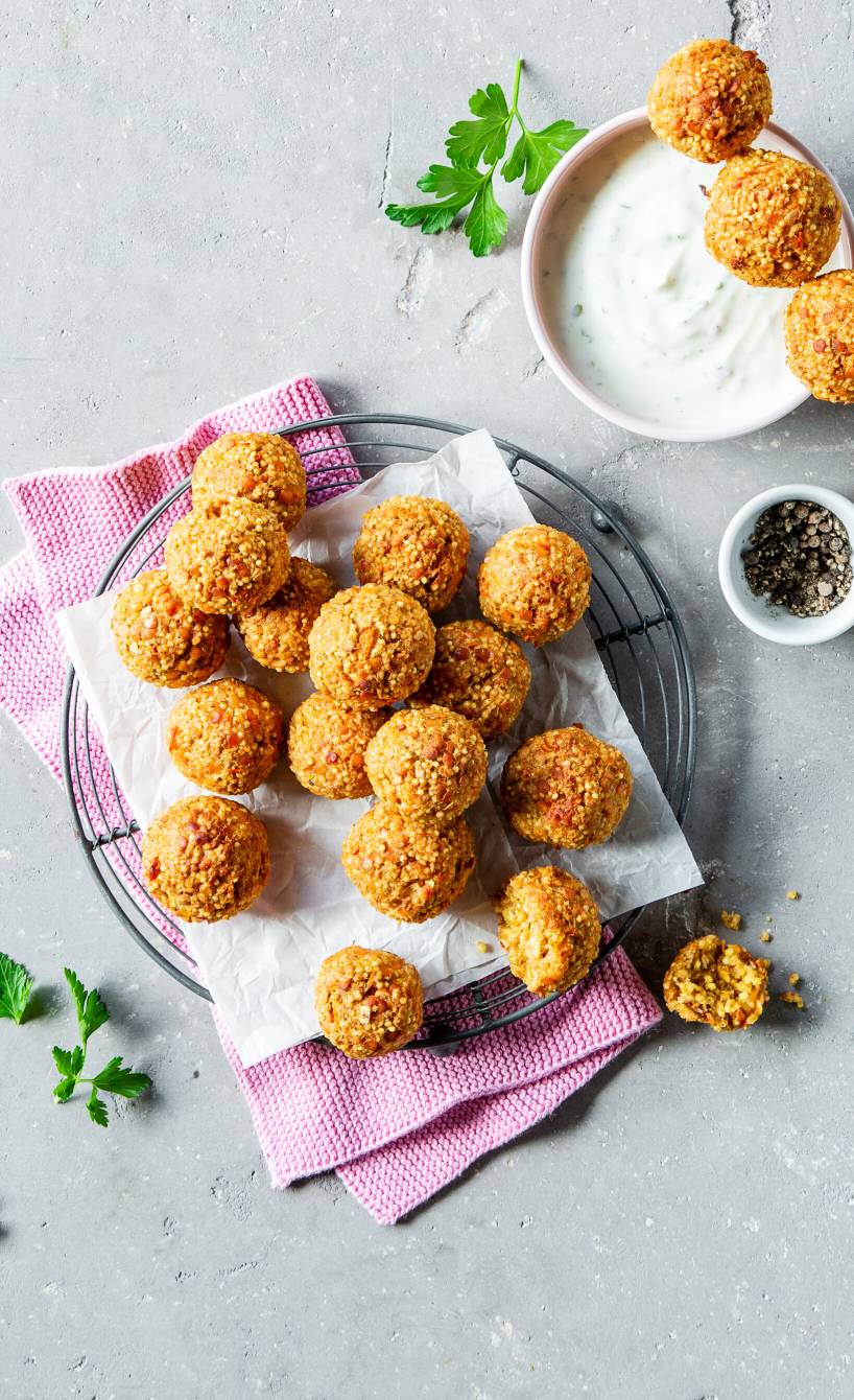 Gebackene Hirse-Linsen-Bällchen mit Haferflocken und Karotten angerichtet auf einem Teller