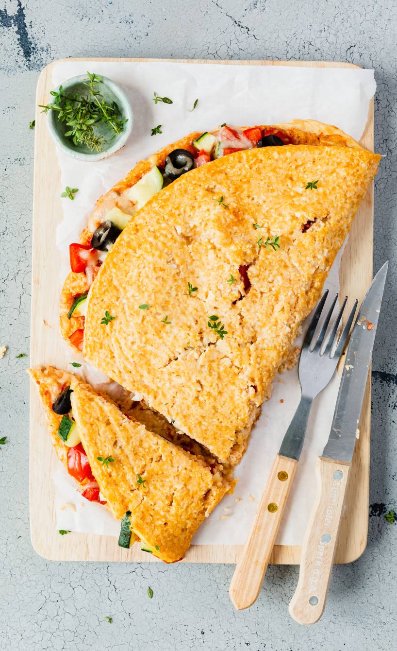 Eine gefüllte Low-Carb-Pizza Calzone auf einem Holzbrett