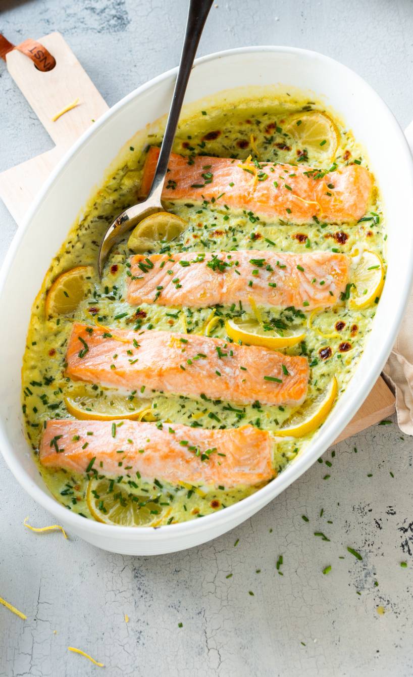 Ofenlachs in Zitronen-Sahnesoße in einer Auflaufform auf einem Tisch