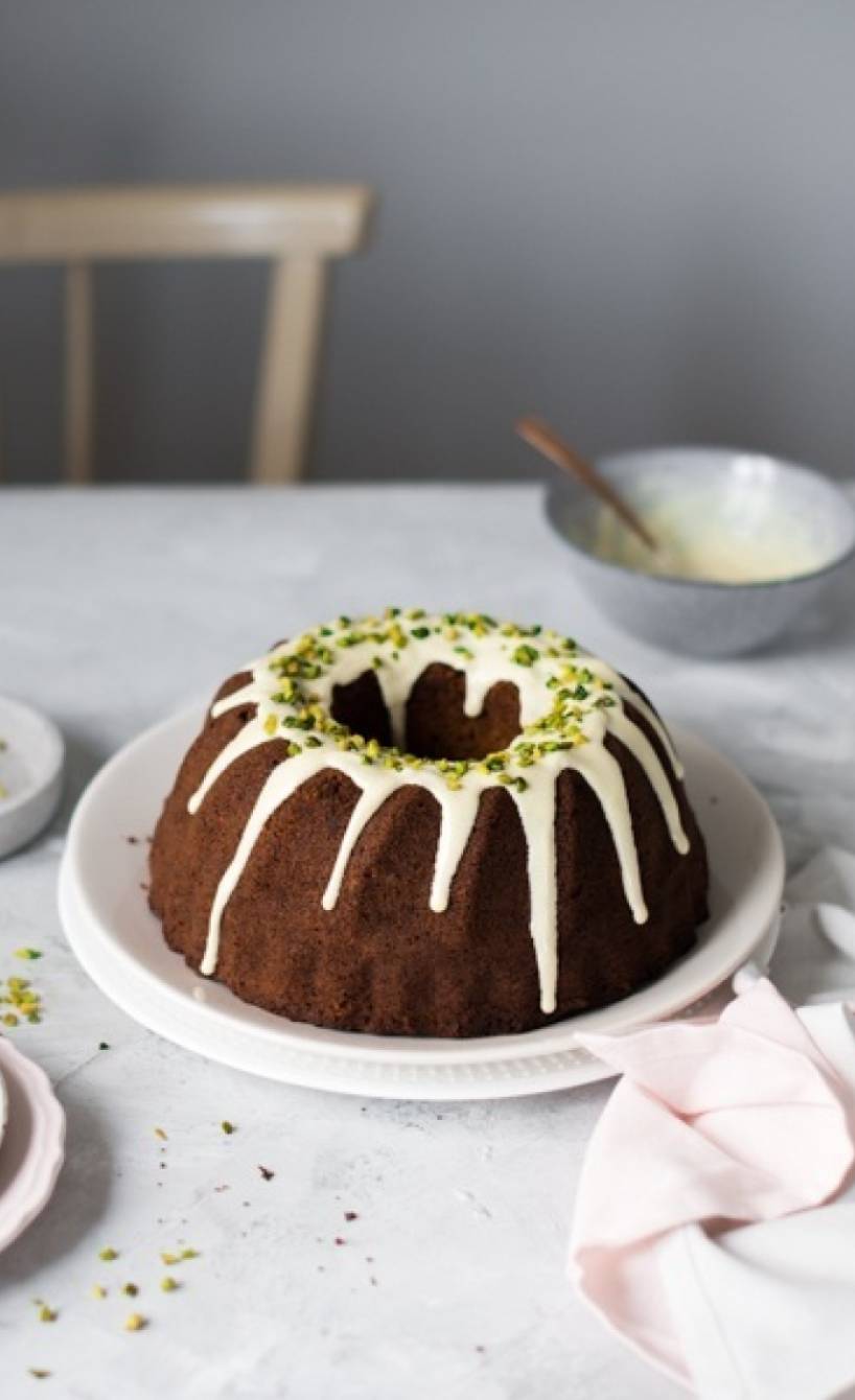 Pistazien-Marzipan-Gugelhupf mit weißem Schokoguss und Pistazienkernen auf einer Kaffeetafel