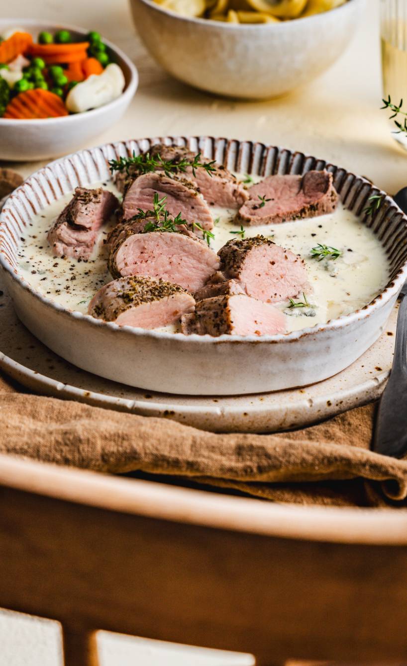 Gebackene Schweinefiletstücke in Gorgonzolasoße auf einem tiefen Teller angerichtet