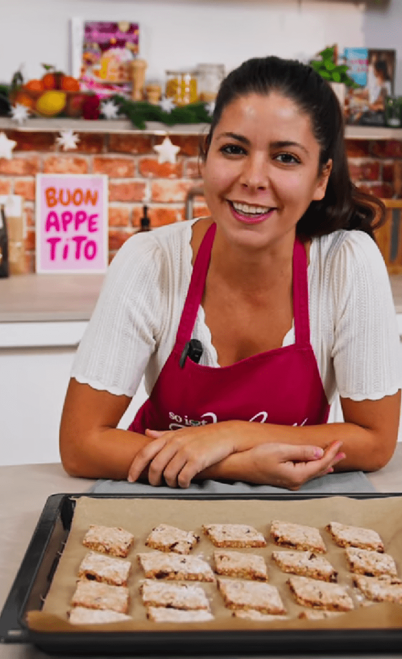 Serena Loddo in de So isst Italien-Küche vor einem Blech selbstgebackener Weihnachtsplätzchen