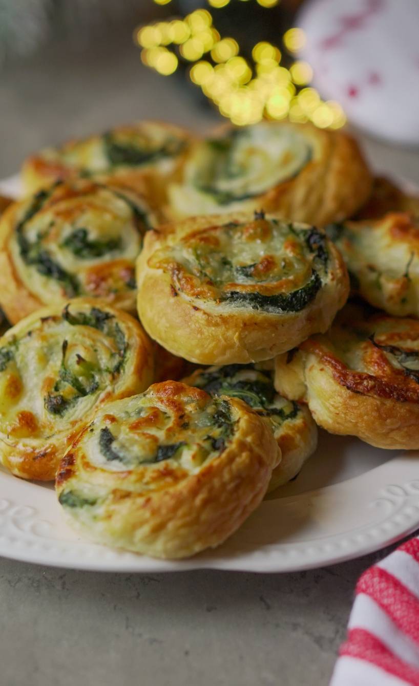 Selbstgebackene Spinat-Blätterteigschnecken gestapelt auf einer Servierplatte auf einem Buffet