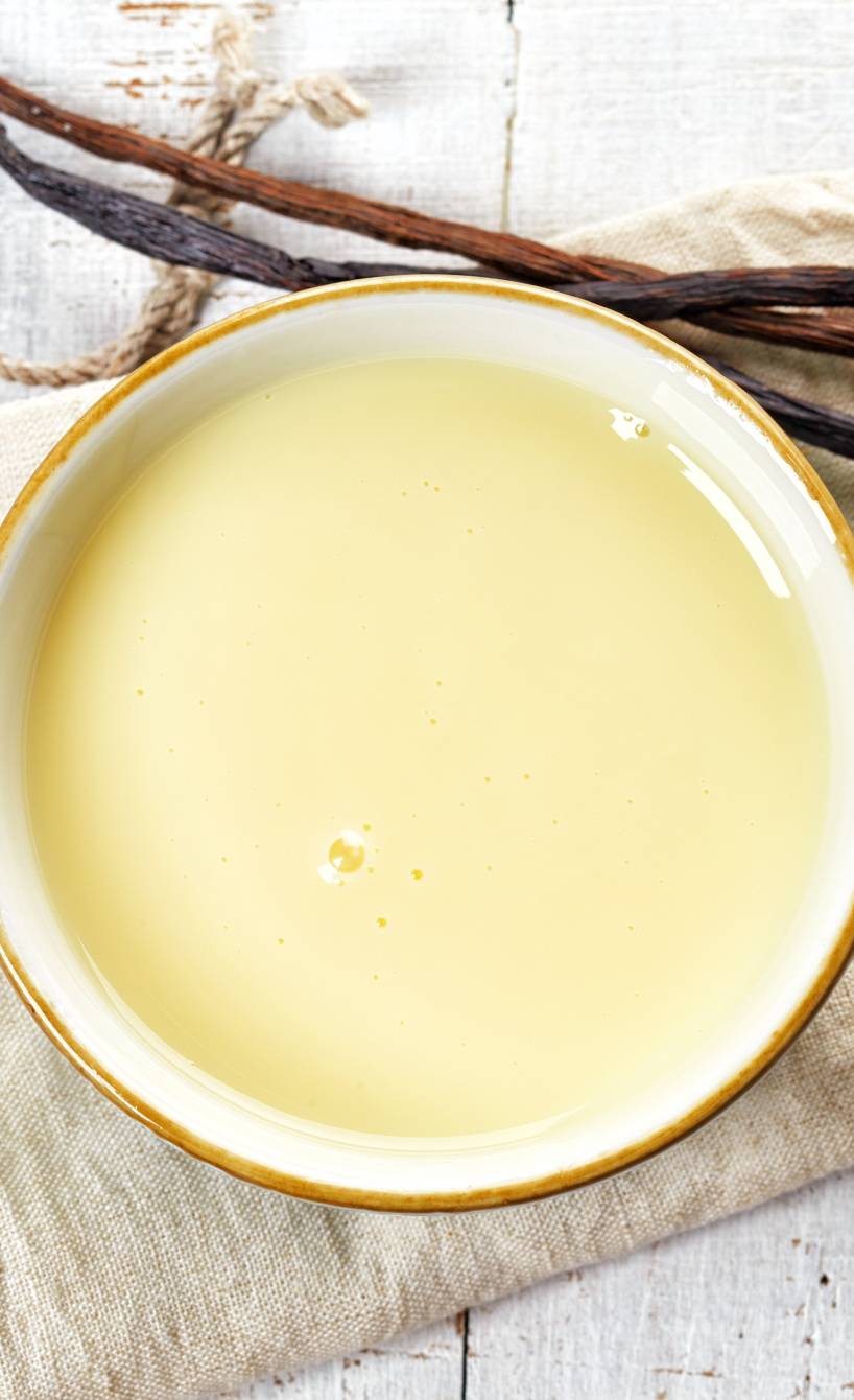 Selbstgemachte Vanillesoße in einer Schale auf einem Tisch, daneben eine Vanilleschote