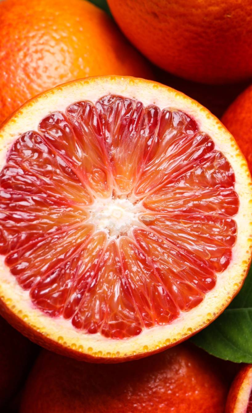 Ganze und halbierte Blutorangen im close up auf einem Holzbrett