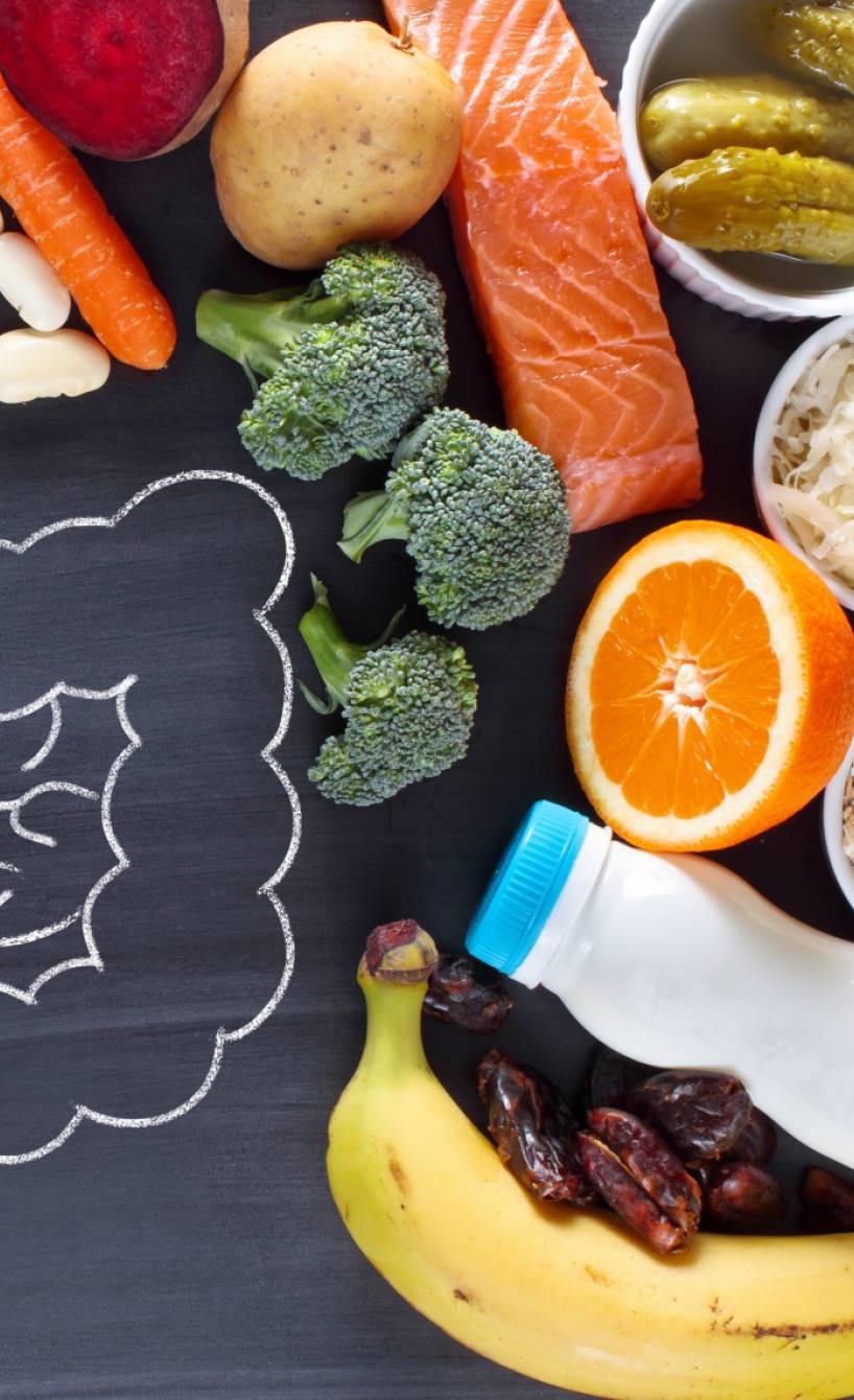 Lebensmittel, die die Darmgesundheit fördern auf einem Tisch, in der Mitte eine Kreidezeichnung des Darms