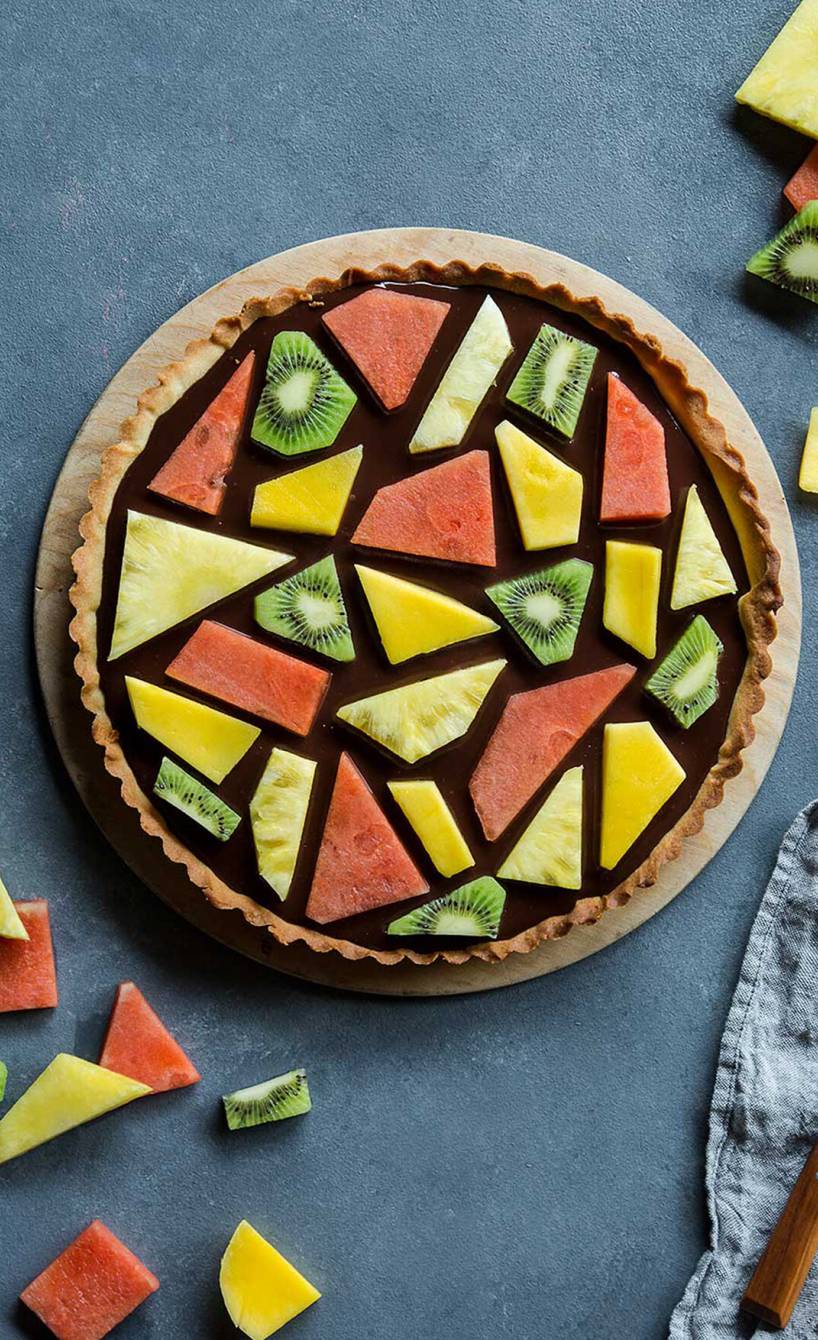 Runder Mosaik-Kuchen mit Ganache und Fruchtmosaik auf einer Kuchenplatte