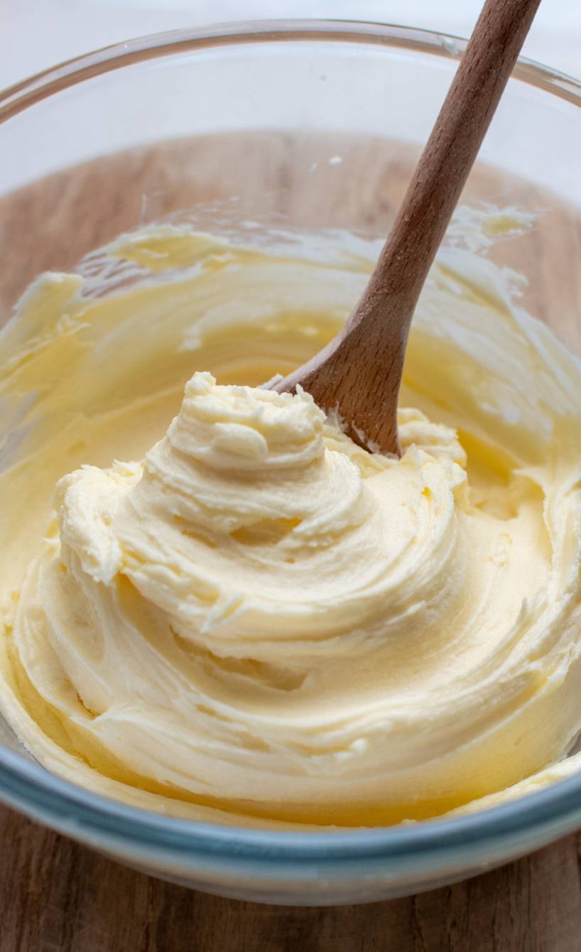 Selbstgemachte italienische Buttercreme in einer Glasschüssel mit Holzlöffel