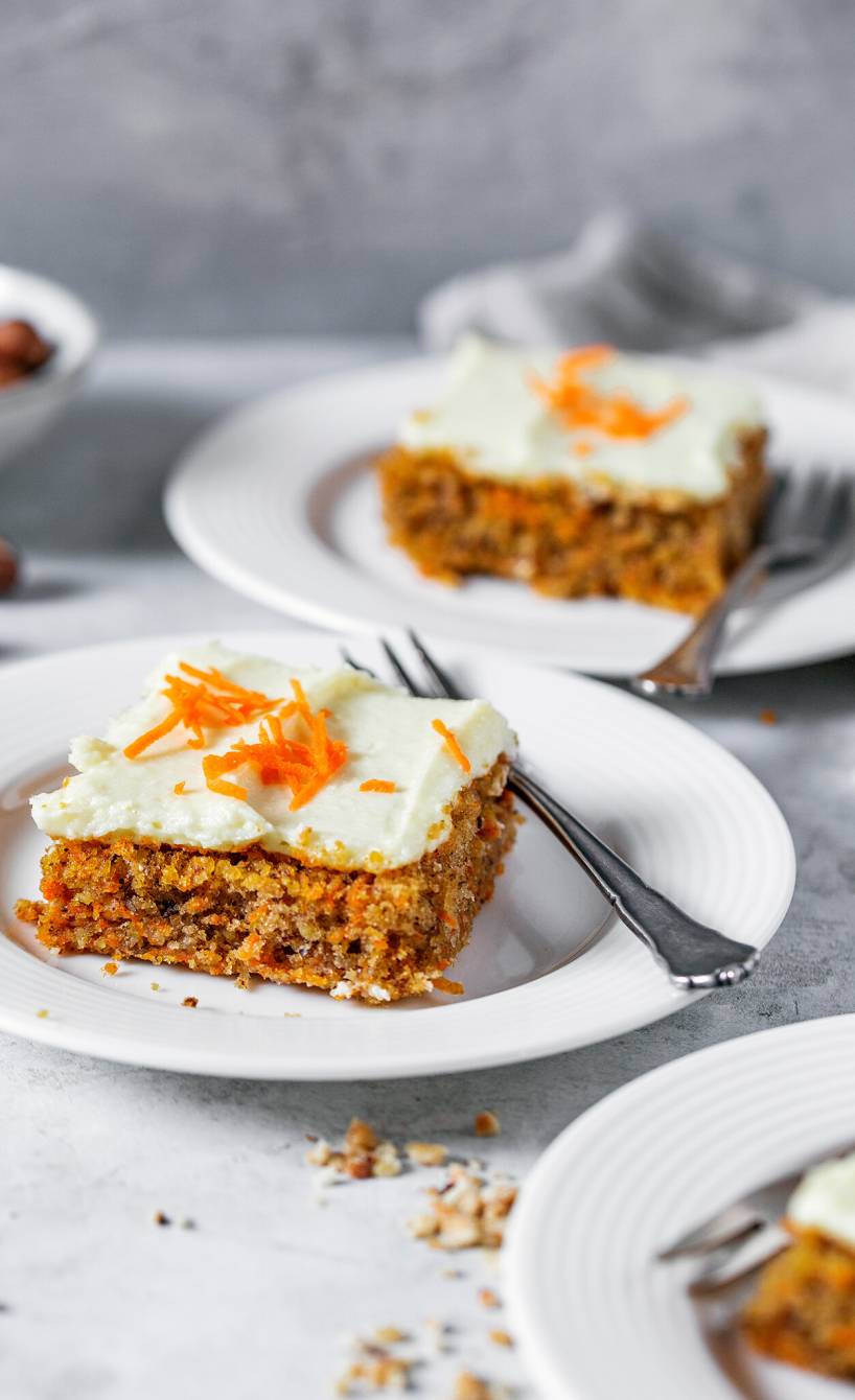 Drei Stücke Karottenkuchen vom Blech mit Frischkäse-Frosting auf Kuchentellern