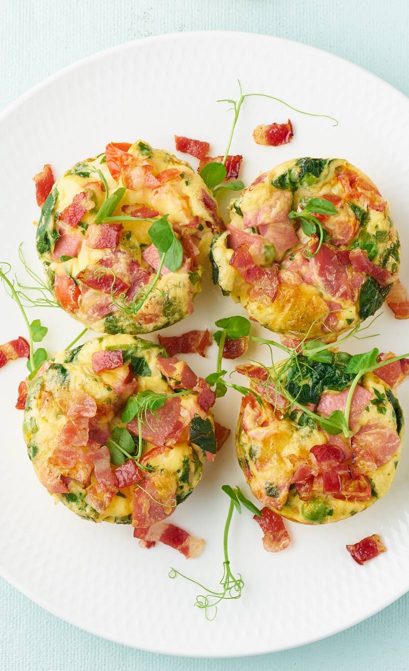 Vier Low-Carb-Frittata-Frühstücks-Muffins mit Ei, Spinat und Pancetta auf einem Teller