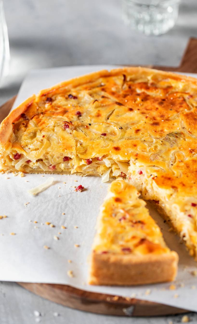 Runder Zwiebelkuchen mit Mürbeteig ohne Hefe angeschnitten auf einem Teller
