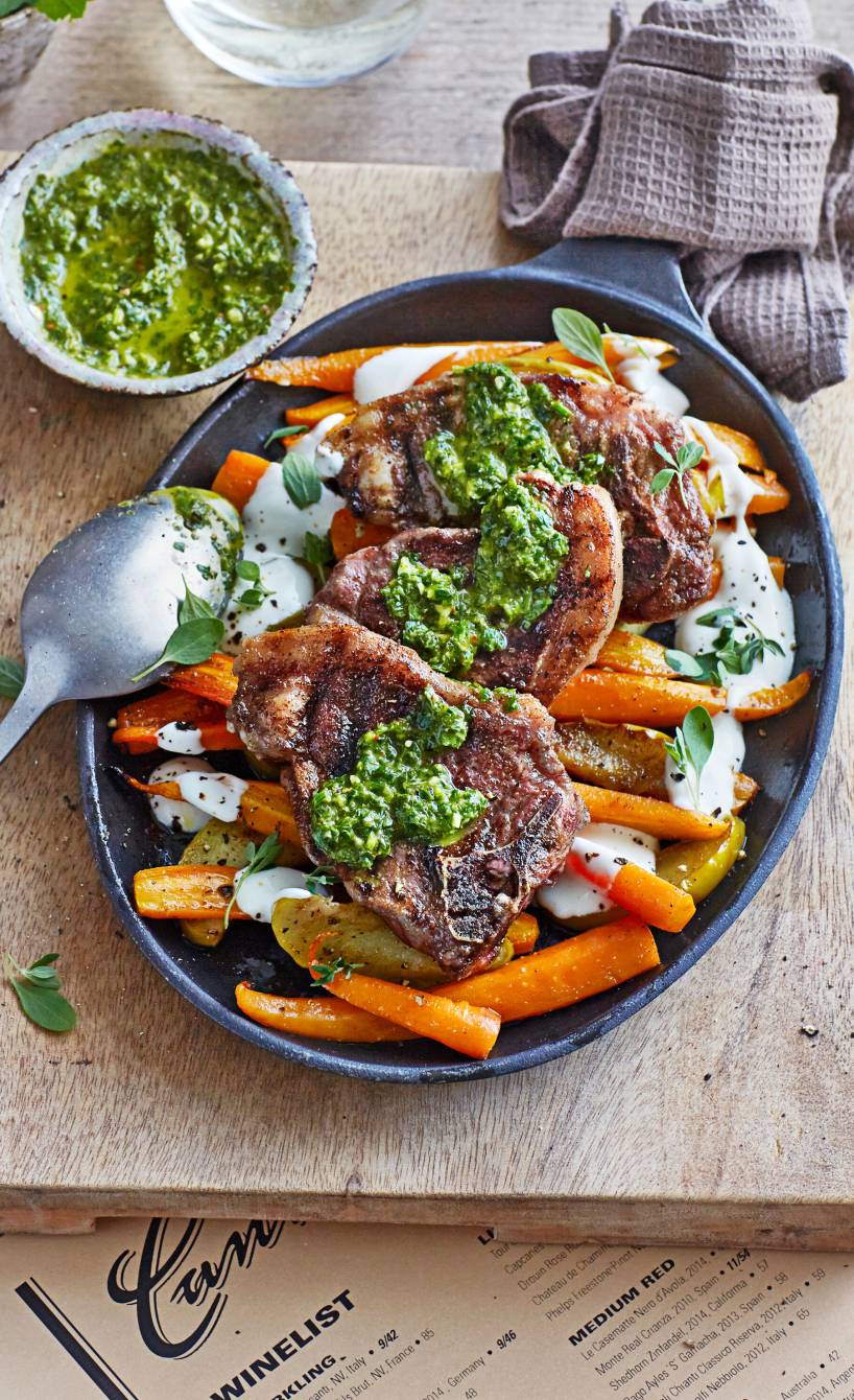 Gegrillte Lammkoteletts angerichtet auf Karotten und Kartoffeln aus dem Ofen getoppt von Kräuteröl und gewürztee saure Sahne