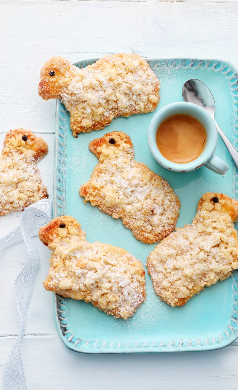 Mehrere selbstgebackene Osterlämmer-Plätzchen aus Mürbeteig mit Kokosstreuseln auf einem Servierteller
