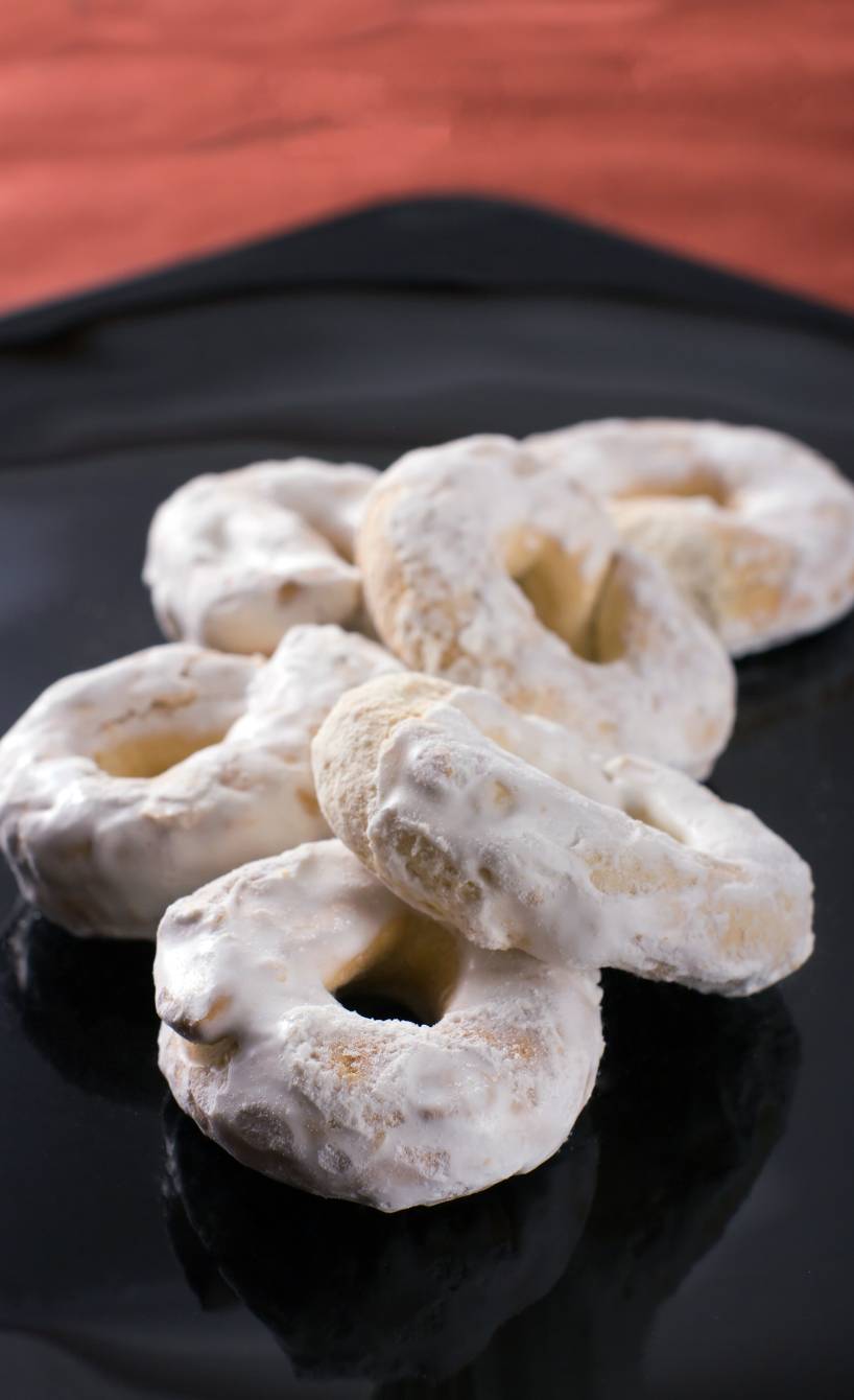 Mehrere selbstgebackene Taralli Osterplätzchen mit Zuckerguss auf einem Teller