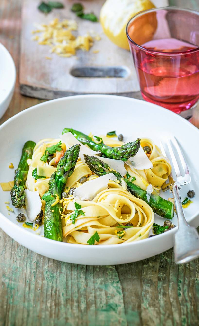 Tagliatelle angerichtet mit gebratenem mit grünem Spargel und Parmesan auf einem Pastateller