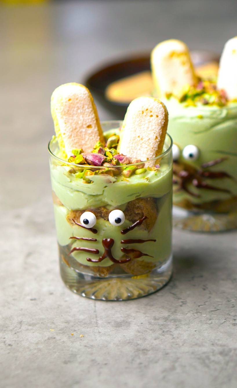 Zwei Gläser mit Oster-Tiramisu dekoriert wie Häschen auf einem Tisch