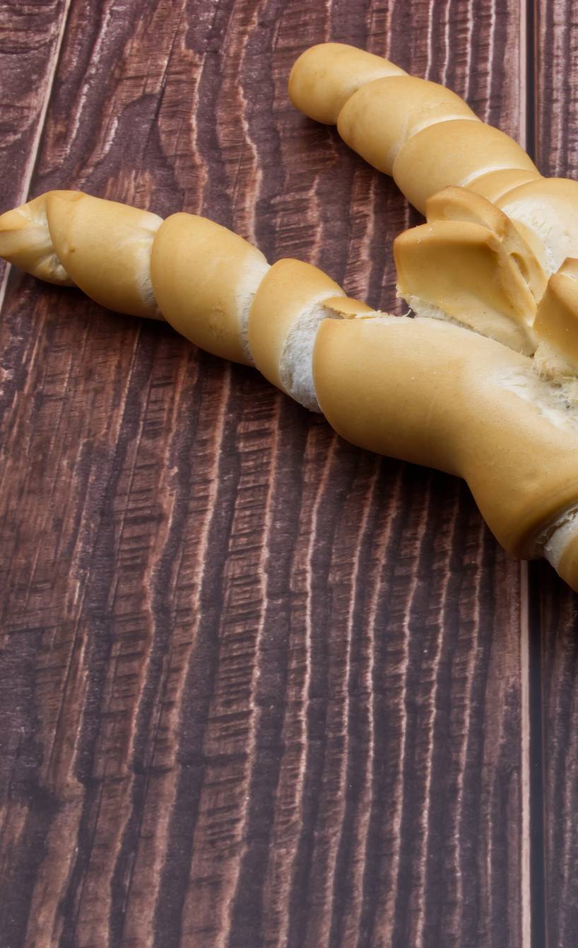 Ein selbstgebackenes Coppia ferrarese italienisches Sauerteigbrot mit Schmalz in X-Form auf einem Holztisch
