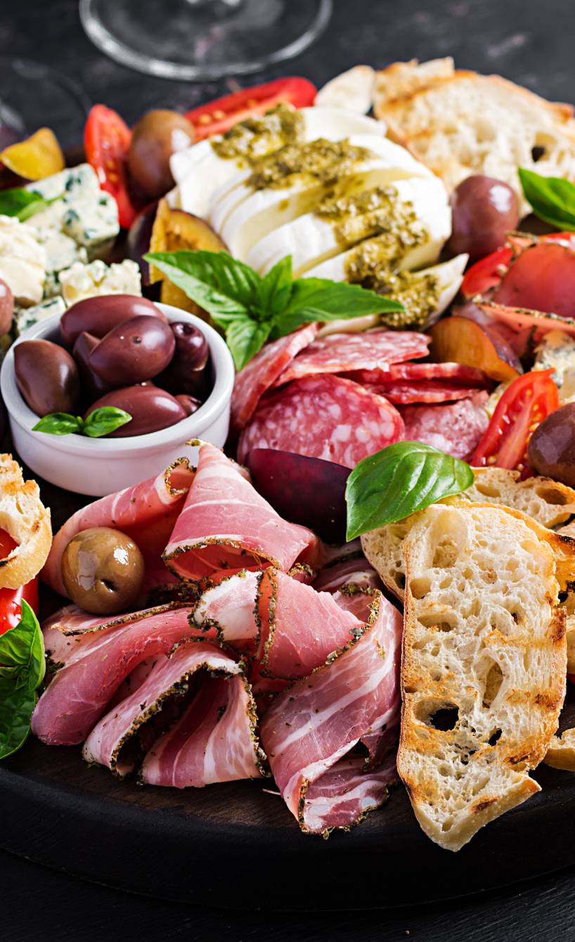 Liebevoll angerichtetes Antipasti Brett auf einem dunklen Holztisch