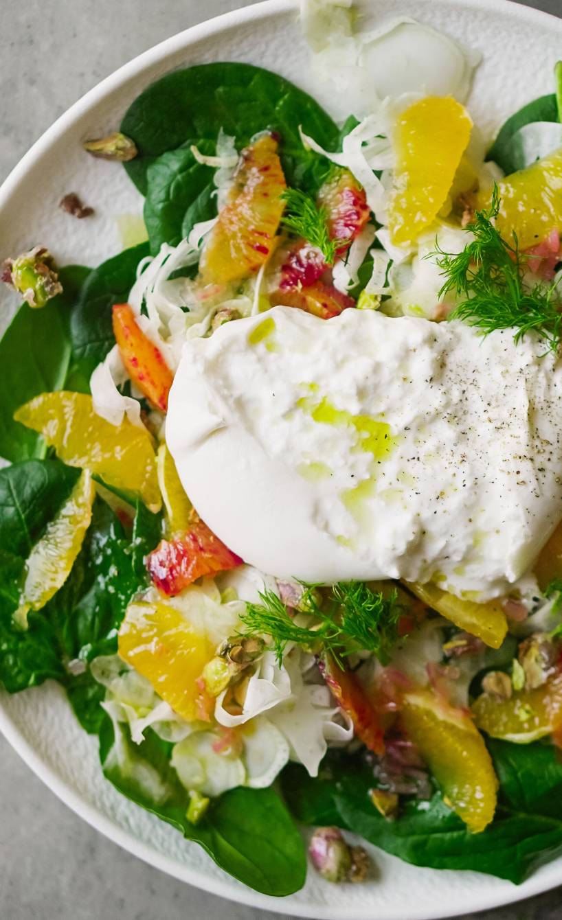 Fenchel-Orangen-Salat mit Spinat und Burrata getoppt von Pistazien auf einem Vorspeisenteller