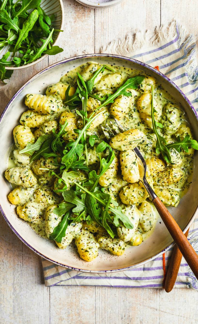 Gnocchi in Kräuter-Rahm getoppt von frischem Rucola auf einem Teller