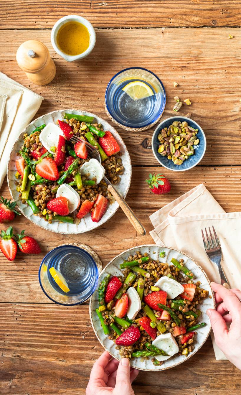 Linsensalat mit grünem Spargel, Erdbeeren und Ziegenkäse getoppt von Pistazienkernen auf einem Teller