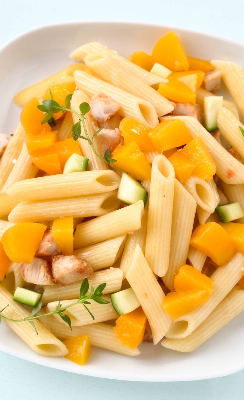 Nudelsalat mit Penne, Gurke und gebratenen Hähnchenbrustfiletstücken angerichtet auf einem tiefen Teller
