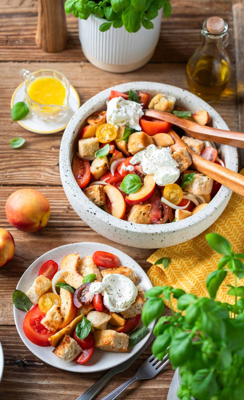 Italienishcer Brotsalat mit Nektarinen und Burrata in einer Salatschüssel und auf einem Teller