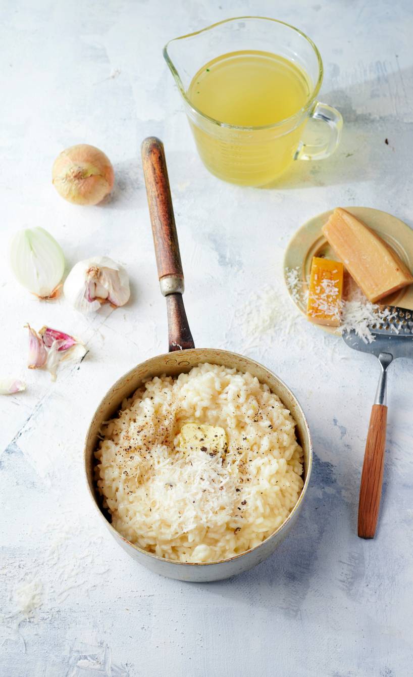 Selbst gekochtes Risotto in einem Stieltopf auf einem Tisch, daneben verschiedene Zutaten Selbst gekochtes Risotto in einem Stieltopf auf einem Tisch, daneben verschiedene Zutaten