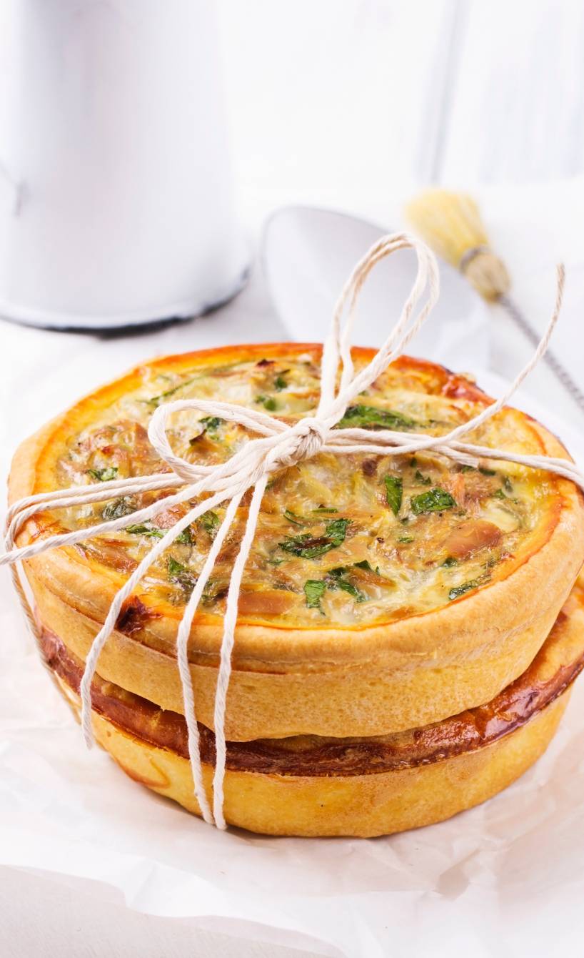 Selbstgebackene Thunfisch-Quiche angerichtet mit Schnur auf einem weiß gedeckten Tisch